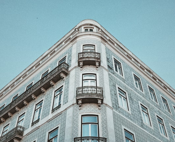 Historic building with ornate facade and arched windows, set on a sunny street in Lisbon with a clear blue sky above